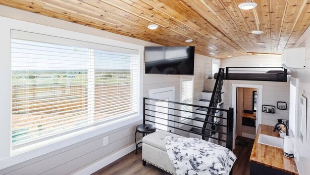 A modern, compact room with a bunk bed, a large window with blinds, a flat-screen TV, and a small kitchenette. - Zion Adventure • Private Hot Tub + Starry Nights (Apple Valley)