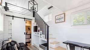 A modern interior with a staircase, a black leather sofa, and a dining area. - Zion Basecamp • Tiny Home Near National Park (Apple Valley)
