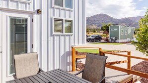 A white mobile home with a deck, two chairs, and a table. - Zion Basecamp • Tiny Home Near National Park (Apple Valley)