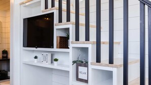 A modern bathroom with a white and black color scheme, featuring a large mirror, a toilet, and a shelf with a plant and a sign. - Zion Basecamp • Tiny Home Near National Park (Apple Valley)