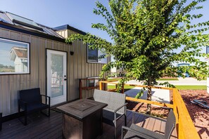 Une terrasse avec du mobilier d’extérieur, une porte avec une fenêtre et un arbre.