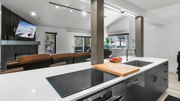 A modern kitchen with a large island, built-in appliances, and a dining area with leather seating. - RMR: Balsam Lodge B8 Condo in The Aspens/ Wilson,WY (Wilson)