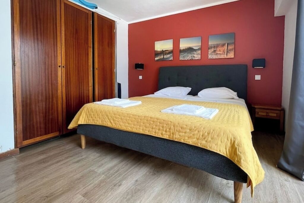 Una camera da letto con un letto, un armadio in legno e opere d'arte alle pareti.