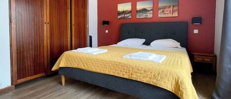 Una camera da letto con un letto, un armadio in legno e opere d'arte alle pareti.