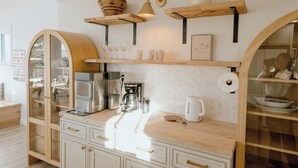 A kitchen with wooden cabinets, a coffee maker, and various kitchenware on the counter.