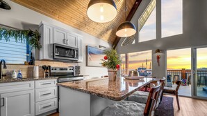 A modern kitchen with granite countertops, white cabinetry, and a large island. - Liezl Lane (Indian Point)