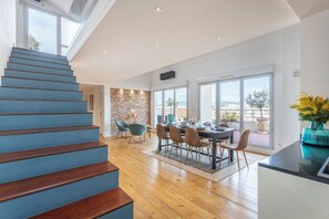 A modern interior with a wooden staircase, a dining area with chairs and a table, and large windows offering a view. - Duplex Panorama Marseillais - Welkeys (Marseille)