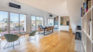 Un'ampia sala da pranzo con pavimento in legno, ampie finestre e vista sulla città.
