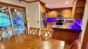 Eine moderne Küche mit Holzschränken, einem Edelstahlkühlschrank und einer Mikrowelle.