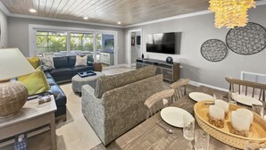 A modern living room with a sofa, a coffee table, and a dining table set for four. - Modern Luxury Private Home with Pool in Siesta Key (Siesta Key)