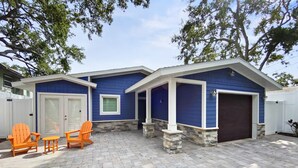 A house with a blue exterior, a garage, and a patio area with two Adirondack chairs and a table. - Modern Luxury Private Home with Pool in Siesta Key (Siesta Key)