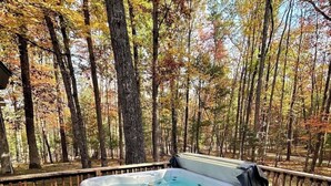 Un jacuzzi en una terraza de madera rodeado de árboles.