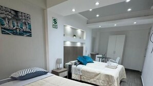 Une chambre d’hôtel moderne avec deux lits, un petit bureau et une salle de bain visible au fond.