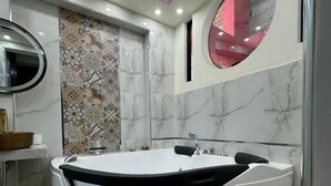 Une salle de bain moderne avec une baignoire sur pieds, un miroir rond et des carreaux décoratifs sur les murs.