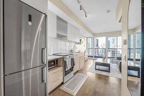 Eine moderne Küche mit Edelstahlgeräten, einem Einbauofen und Blick auf die Stadt durch große Fenster.