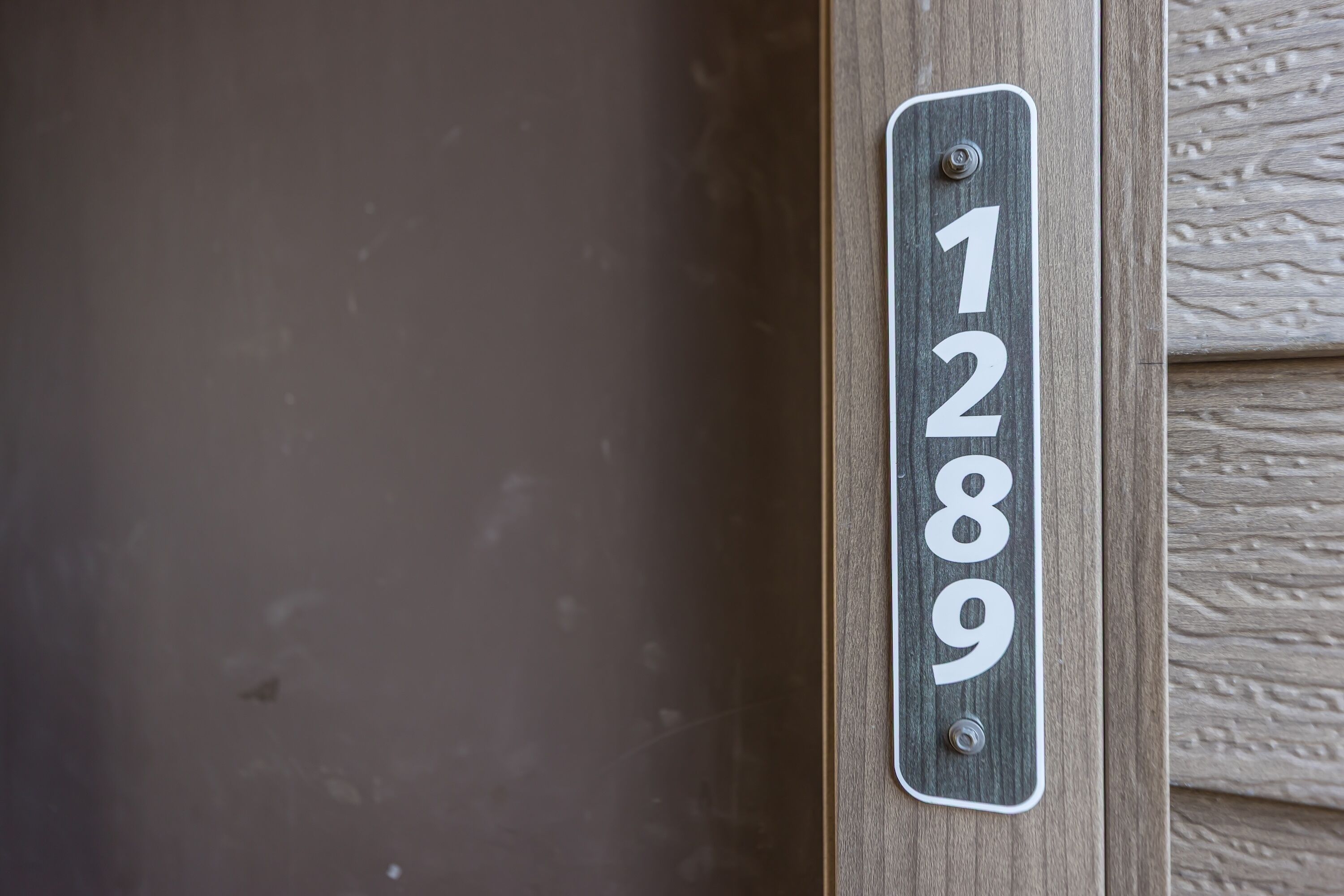 A house number sign mounted on a wooden door.