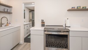 Ett modernt kök med vita skåp, en ugn i rostfritt stål och en bänkskiva med ett knivställ.