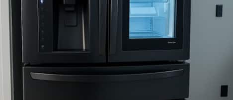 A black LG refrigerator with a water dispenser and a freezer compartment.