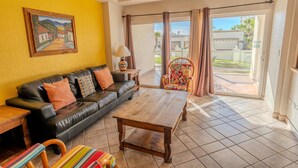 A living room with a sofa, a wooden coffee table, a colorful chair, a lamp, and a painting on the wall. - Delphin 103, Las Palmas Resort (Puerto Peñasco)