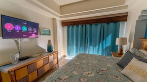 A hotel room with a bed, a television, a wooden console table, and a window with curtains. - Grande 105, Las Palmas Resort (Puerto Peñasco)