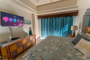 Ein Hotelzimmer mit einem Bett, einem Fernseher, einem Holzkonsolentisch und einem Fenster mit Vorhängen.
