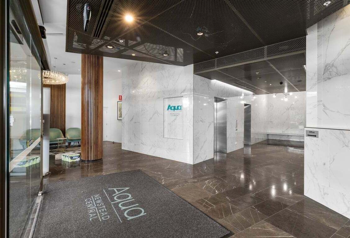 A modern lobby with a marble floor, a reception desk, and a sign for 'Aqua'.