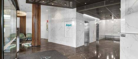 A modern lobby with a marble floor, a reception desk, and a sign for 'Aqua'.