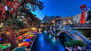 A riverside restaurant with outdoor seating and a bridge. - Stroll to the Dome Sleek 1BR Near Downtown (San Antonio)