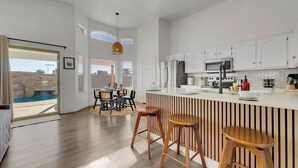 Una cucina moderna con mobili bianchi, un'isola centrale e sgabelli in legno.