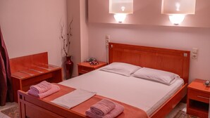 Een hotelkamer met een houten bed, twee nachtkastjes, een spiegel en een wandlamp.
