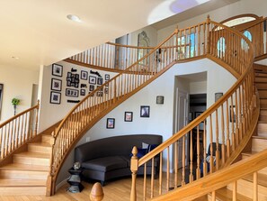 A wooden staircase with a curved design, a black sofa, and framed pictures on the walls.