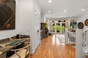 A modern interior with a wooden floor, a stone fireplace, and a dining area with a bench and table. - Modern Big Sky Retreat  | Hot tub + Shared Pool (Big Sky)