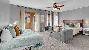 Een slaapkamer met een bed, een bank, een plafondventilator en een nachtkastje.