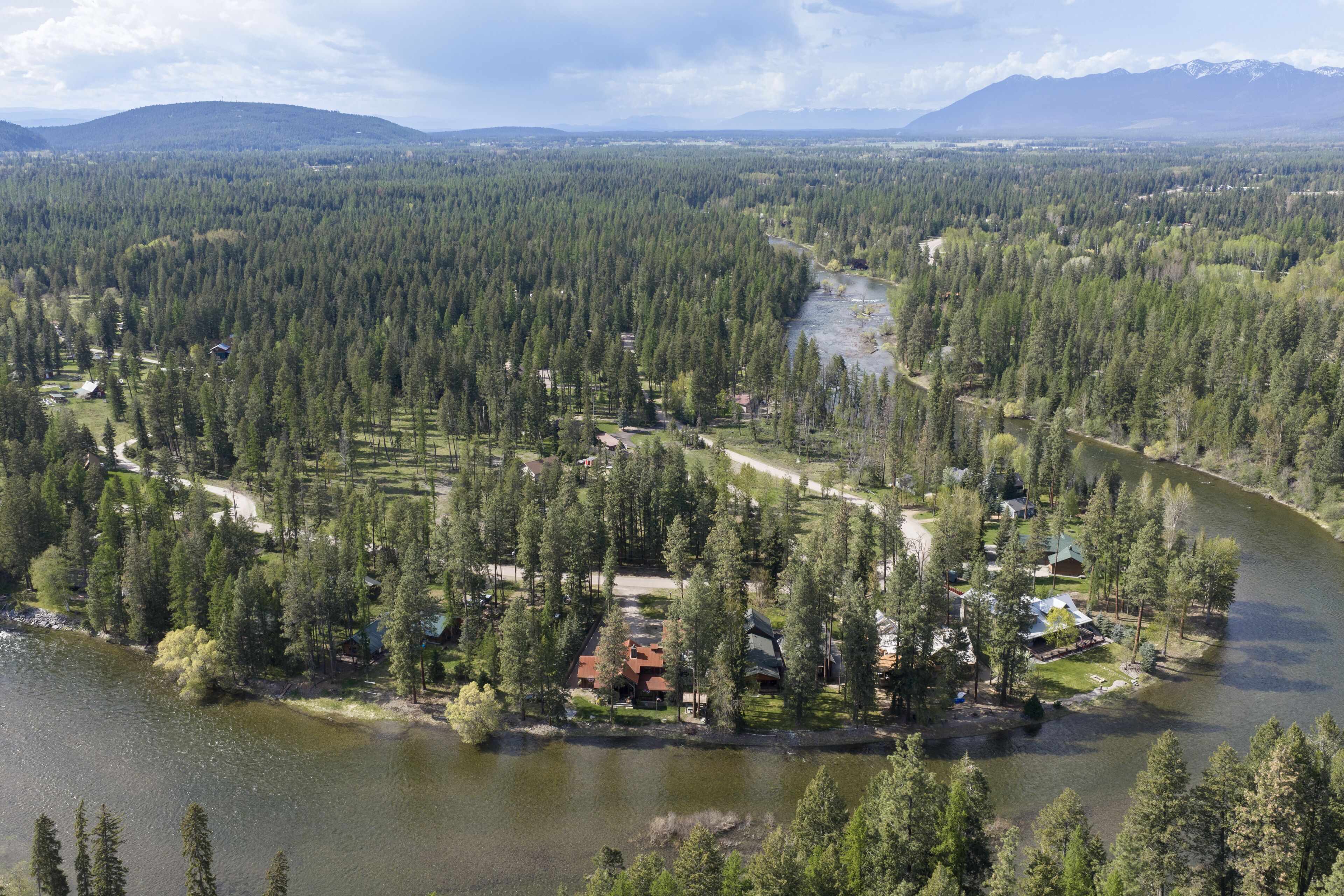 A river surrounded by dense forest and houses with visible roads and paths.