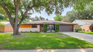 A single-story house with a garage, a well-maintained lawn, and a large tree in the front yard. - Charming 4-bedroom 2.5 Bath one level house with garage 7 miles from NRG stadium (Houston)