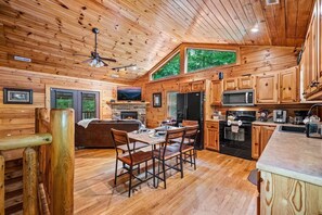 Ein Interieur einer Hütte mit Essbereich, Küche und Kamin.