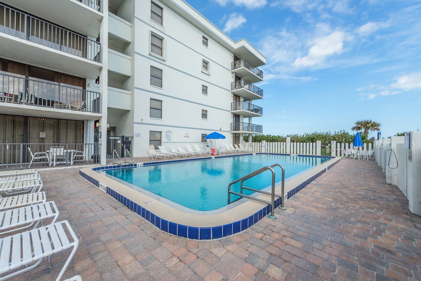 A swimming pool with lounge chairs and a building with balconies.