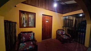 Una habitación con dos sillas de madera, una puerta de madera y un ventanal con cortinas.