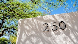 A white wall with the number "250" in black, surrounded by trees. - Cozy 2BR W/ Desk • Fast Wi-Fi • Easy Parking (Tucson)