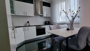 Eine moderne Küche mit weißen Schränken, einem eingebauten Ofen und einem Essbereich mit Tisch und Stühlen.