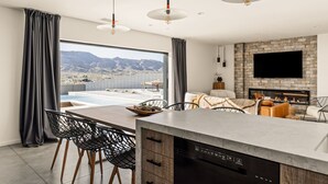 A modern kitchen with a built-in dishwasher, a dining area with a view of mountains, and a fireplace. - Celestine - Modern w Pool Near Park Entrance (Joshua Tree)