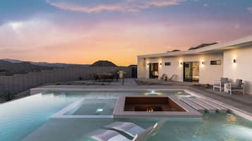 Un espace piscine extérieur moderne, doté d’un jacuzzi, de chaises longues et d’un coin repas.