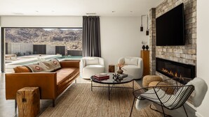 A modern living room with a fireplace, a pool view, and a flat-screen TV. - Celestine - Modern w Pool Near Park Entrance (Joshua Tree)