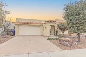 A single-story house with a beige facade, a red-tiled roof, and a white garage door. - Luxe Tuscan Villa - Organ Mtn Views, Patio Living, Sonoma Golf (Las Cruces)