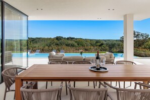 A modern outdoor dining area with a wooden table and wicker chairs, overlooking a swimming pool and lush greenery. - Villa Lavis (Istria - Sveti Lovreč) (Sveti Lovreč)