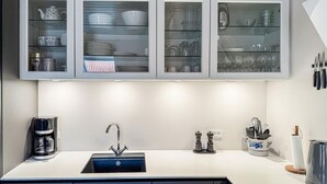 A modern kitchen with a built-in sink, a coffee maker, and glass-fronted cabinets above the counter. - 2 bedroom amazing apartment in Gudhjem (Gudhjem)