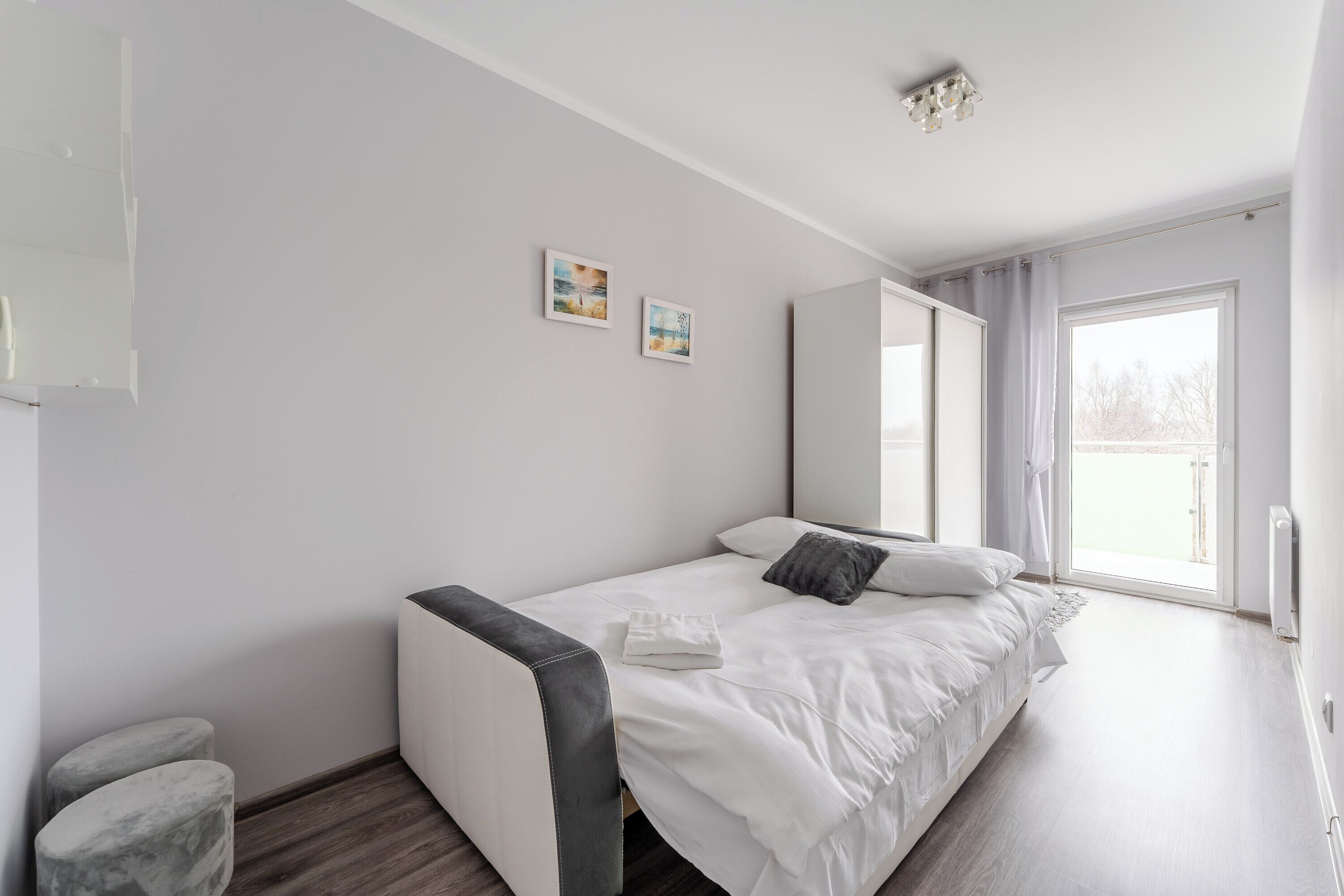 Une chambre à coucher moderne avec un grand lit, une table de chevet, une chaise et une fenêtre donnant sur un beau paysage.