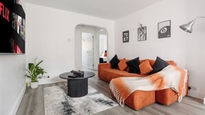 A modern living room with a sectional sofa, a coffee table, and a large bookshelf. - Modern 2BR Flat, 20 mins train to Central London, 7mins to Selhurst Park Stadium (London)