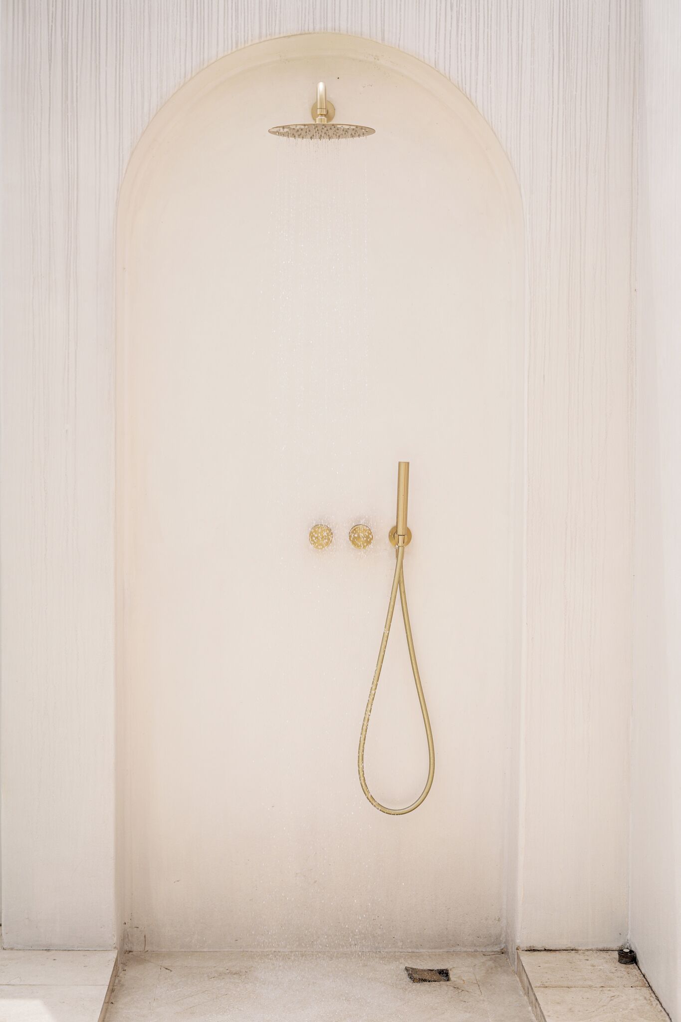 A white shower enclosure with a gold showerhead and controls.