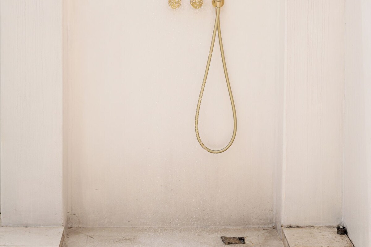 A white shower enclosure with a gold showerhead and controls.